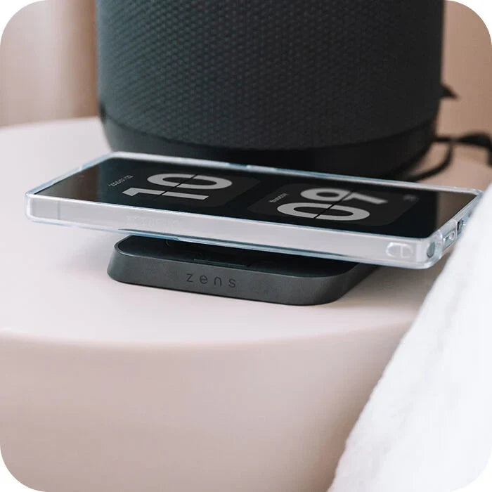 Wireless charging pad with smartphone on a beige surface, branded 'zens'.