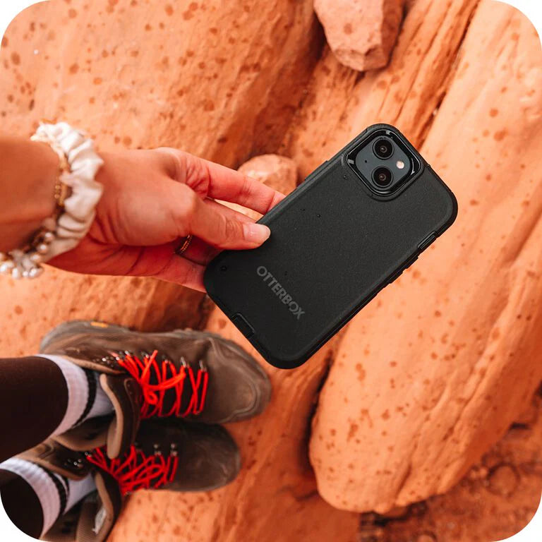 Person holding a black OtterBox phone case with rocky background