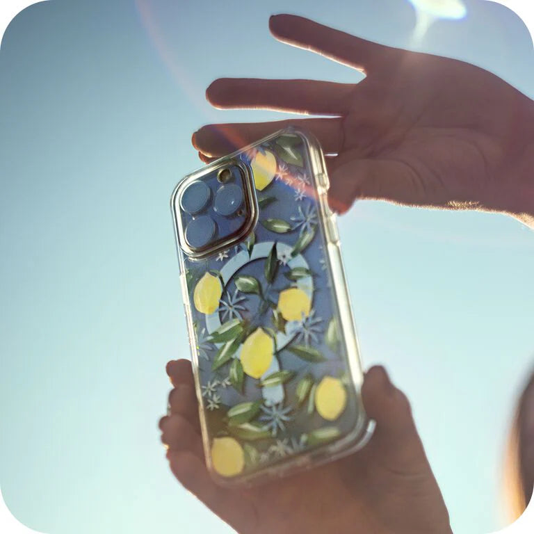 Phone case with lemon design held by a hand against a light blue background
