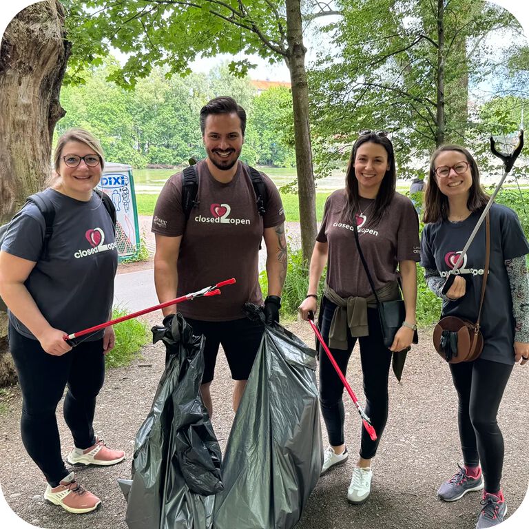 Four people participating in a community cleanup event in a park.