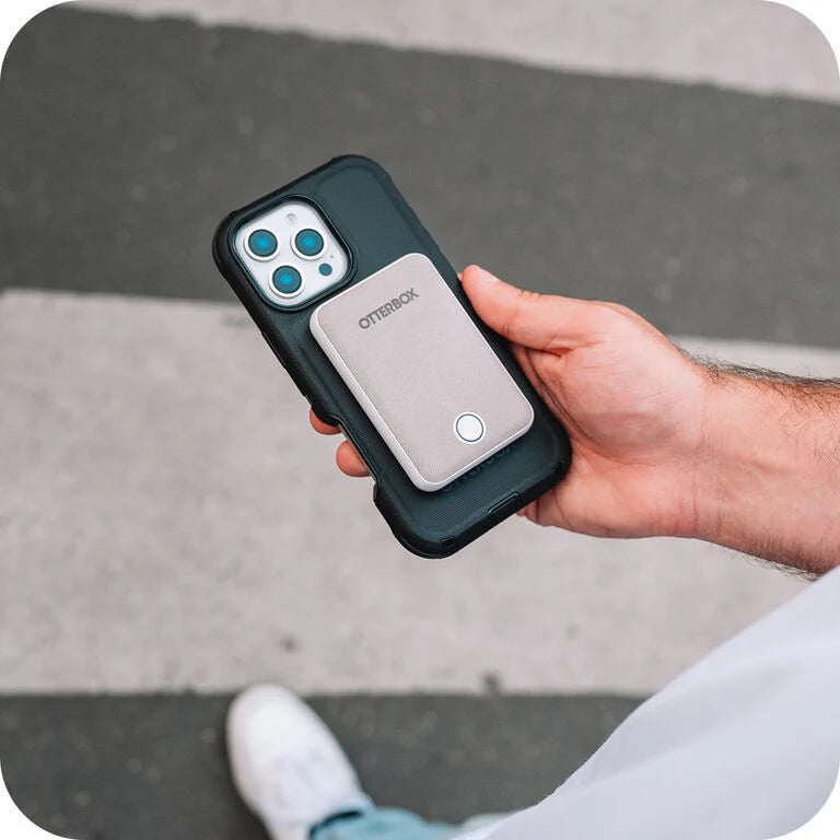 Hand holding a phone case with 'OtterBox' branding on a pavement background