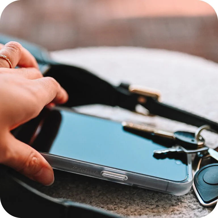 Person holding a smartphone with a keychain on a blurred background