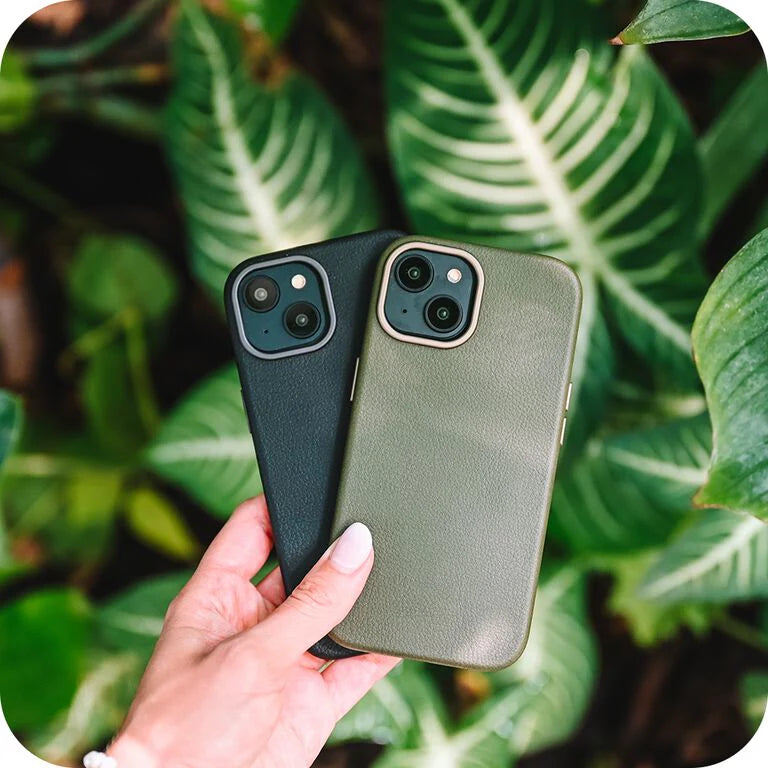 Two phone cases, one black and one green, held against a leafy background.