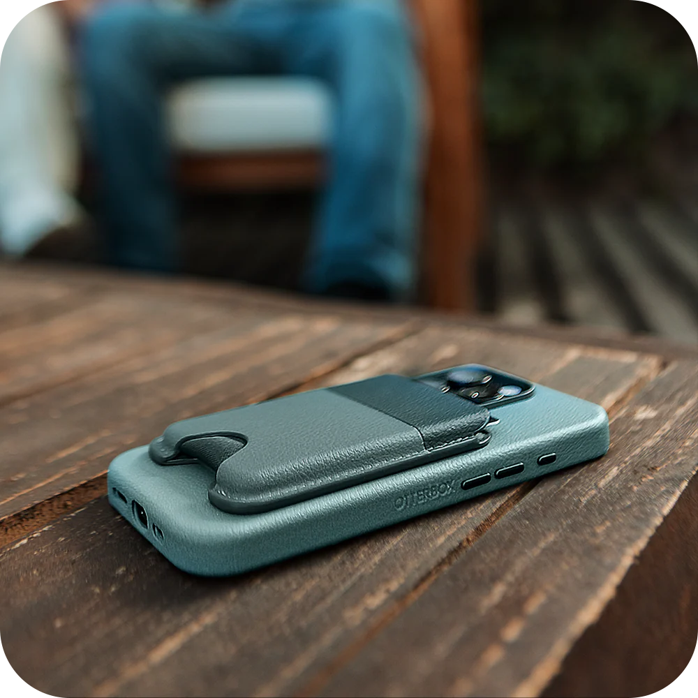 Teal phone case with card holder on a wooden surface, blurred background