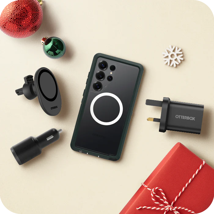 Phone case, car charger, travel adapter, and gift box on a beige surface with Christmas decorations.